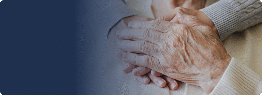 Close-up of two people gently holding hands.