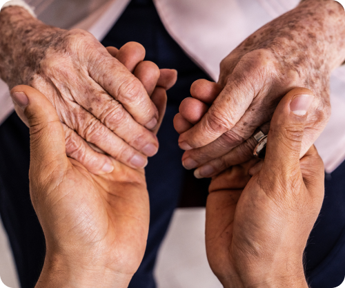Close-up of one person gently holding another’s hands, conveying support and compassion.