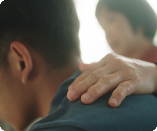 Caregiver offering comfort by placing a hand on a patient’s shoulder.