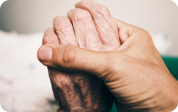 Close-up of two people gently holding hands in support