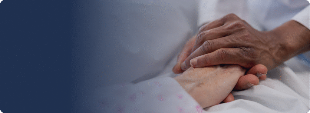 Caregiver gently holding an older adult’s hands in comfort.