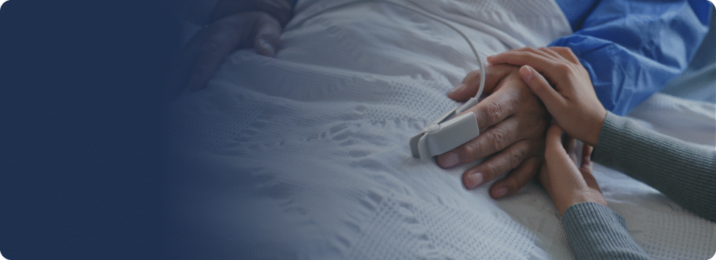 Caregiver gently holding the hand of an older adult for comfort.


