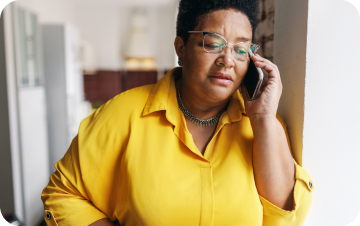Woman speaking on the phone in a bright room, appearing calm and focused.