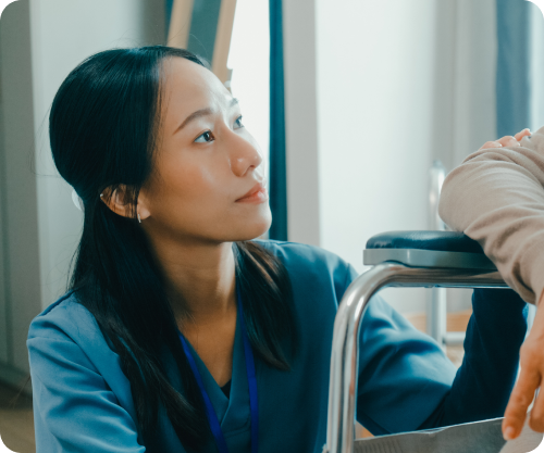 Nurse in blue scrubs speaking with a patient during a home visit.