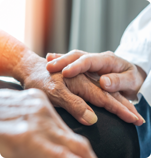 Close-up of a caregiver gently holding an older adult’s hand in support.