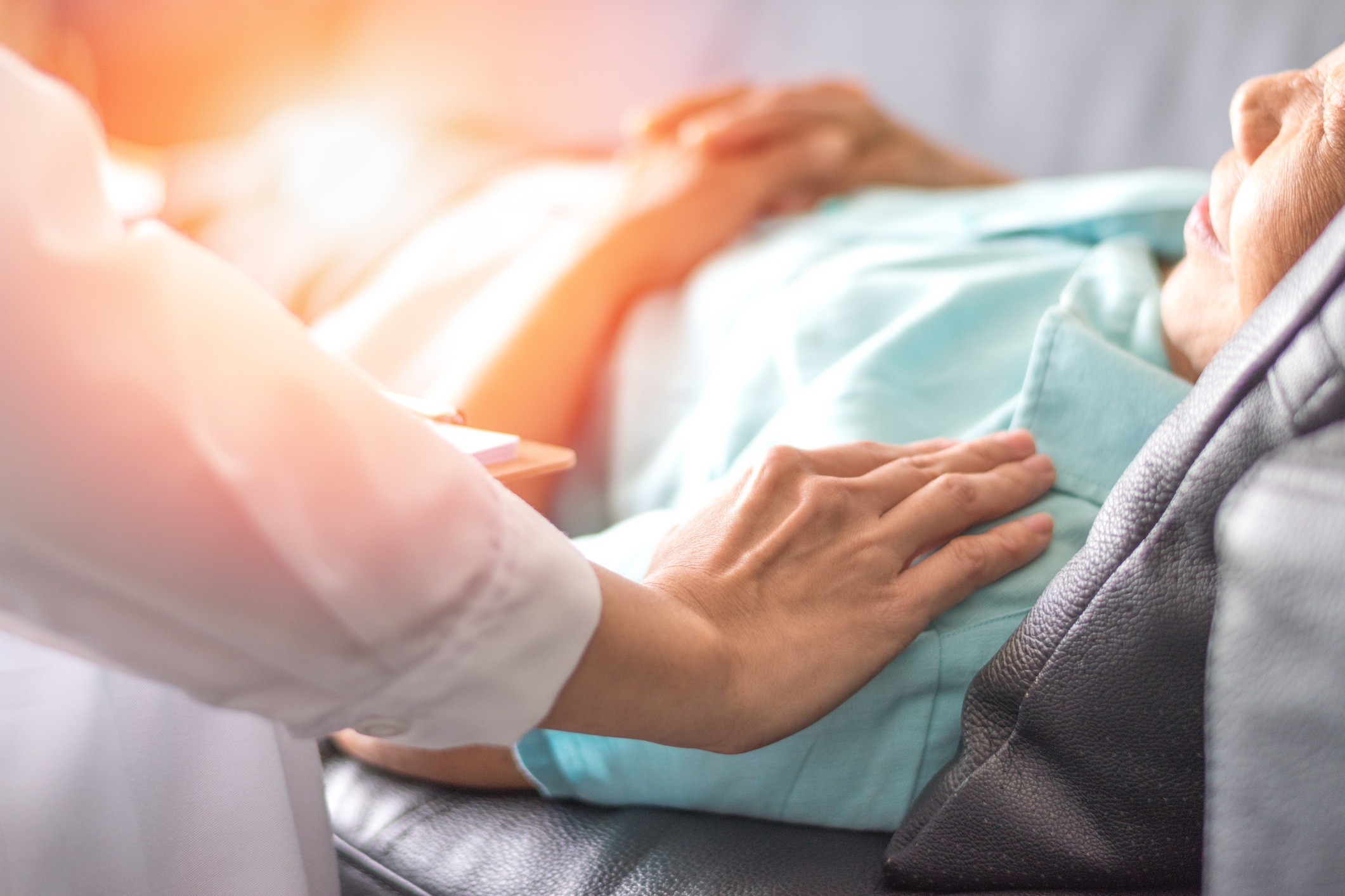 Caregiver gently placing a hand on a patient’s chest to provide comfort during hospice care